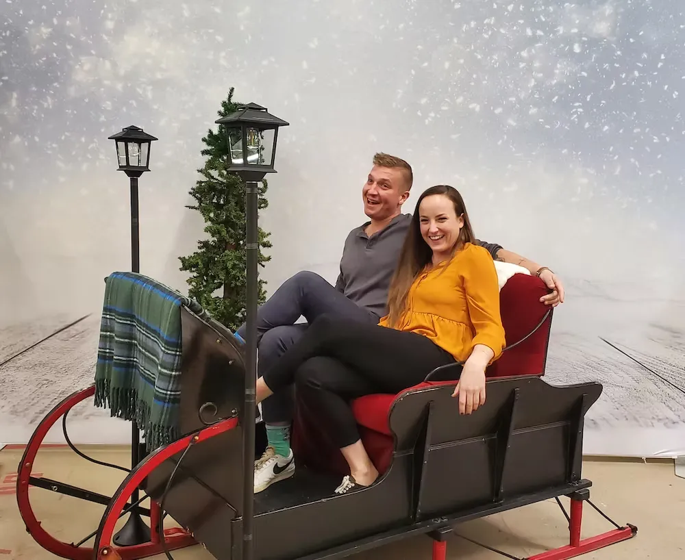 Complete sleigh photo booth package with winter-themed props, backdrop and professional attendant for holiday events